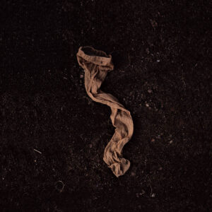 A single pantyhose lying on the ground on a black background