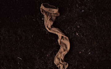 A single pantyhose lying on the ground on a black background